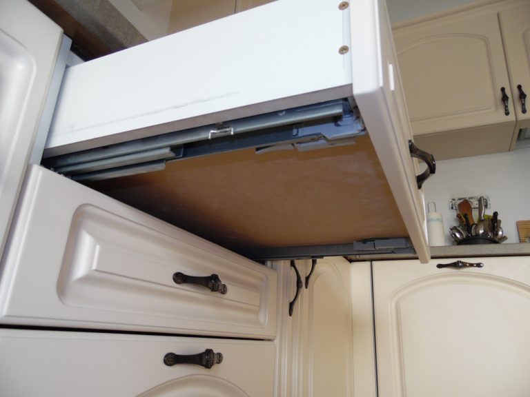 Sertar deschis al unei bucătării la comandă, evidențiind glisierele montate sub sertar pentru rezistență și o culisare fină.