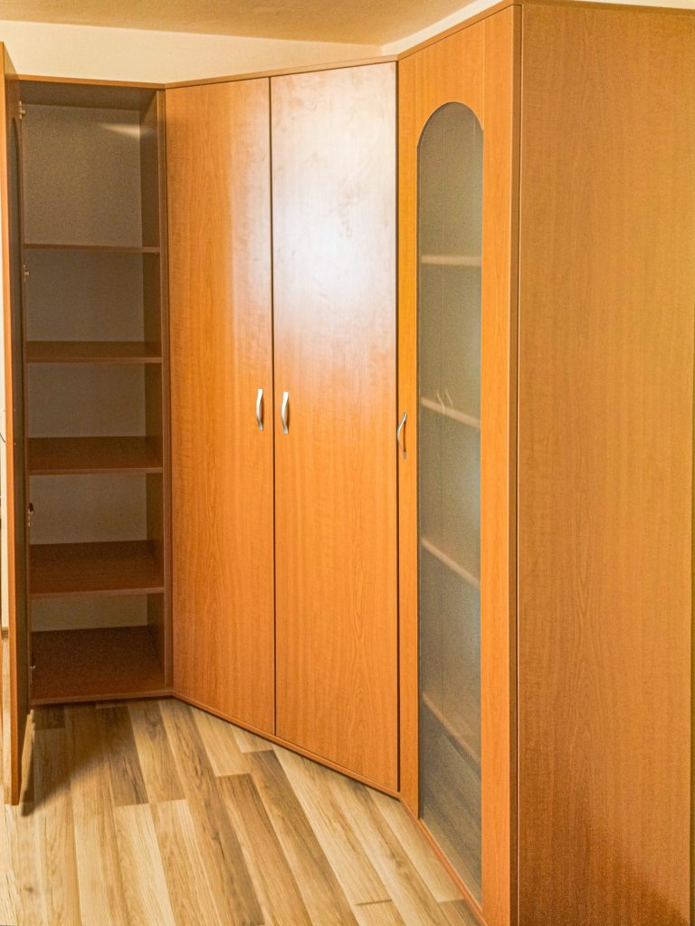Detaliu interior al corpului stâng dintr-un dressing pe colț, cu rafturi și ușă clasică cu oglindă.
