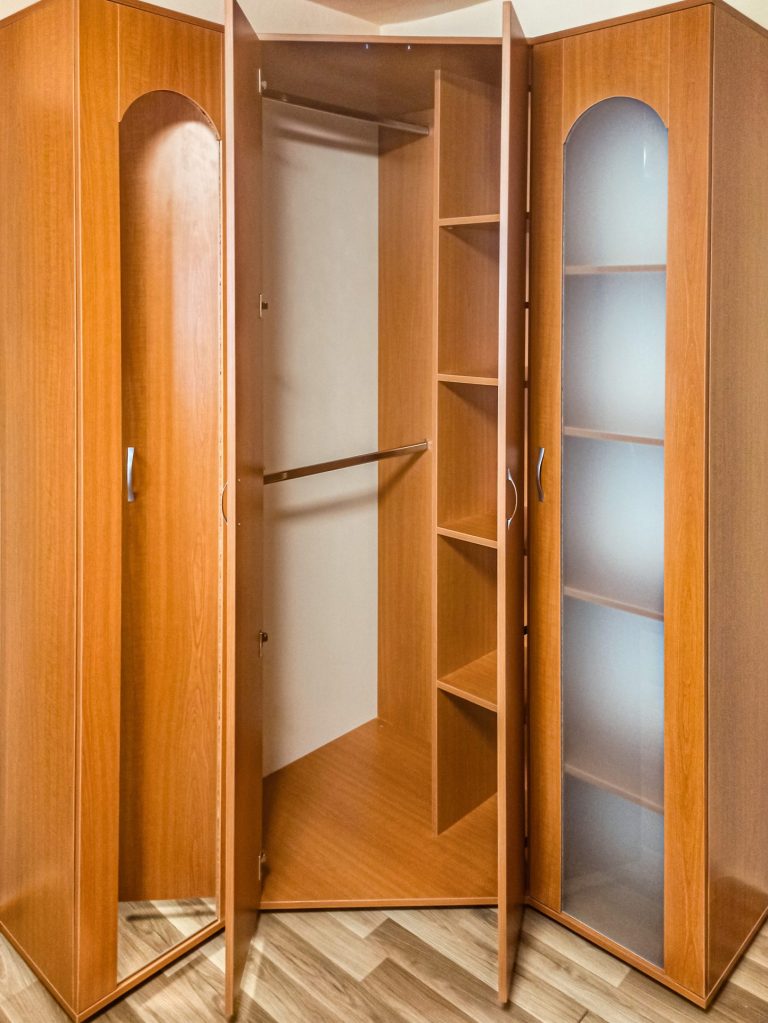 Interiorul corpului central al dressingului pe colț, cu două bare pentru umerașe și o coloană de rafturi.