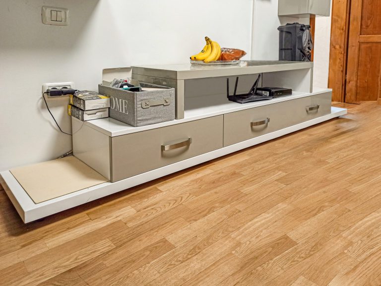 Prim-plan cu cele trei sertare ale corpului inferior de la un mobilier de living modern, cu fronturi din MDF bej lucios și mânere metalice.