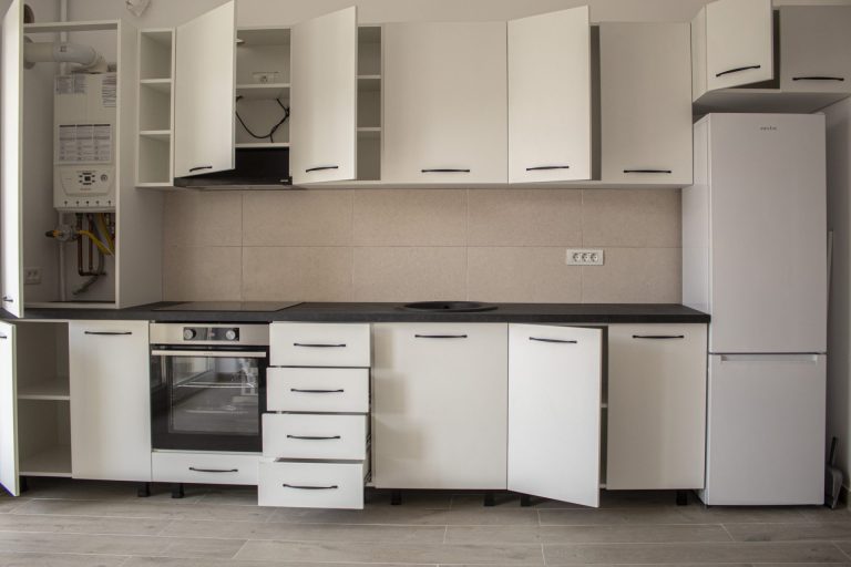 Detaliu cu ușa deschisă a unui corp înalt de mobilier, unde se observă o centrală termică perfect integrată în structură.