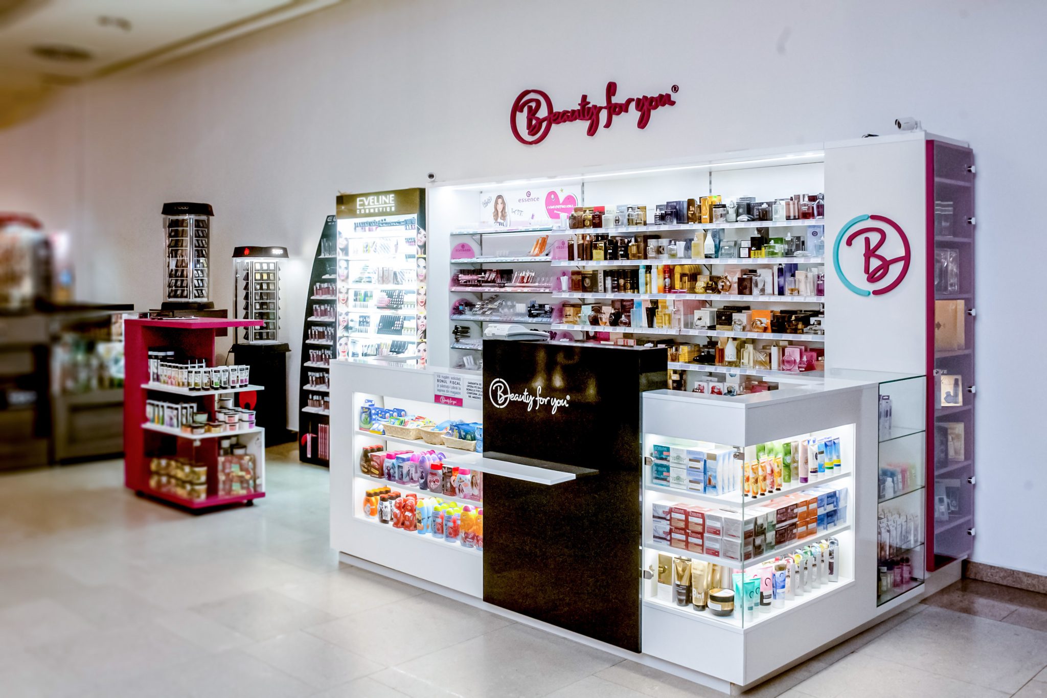 Insula comerciala completa cu mobilier la comanda alb si roz, standuri mobile si zona receptie.