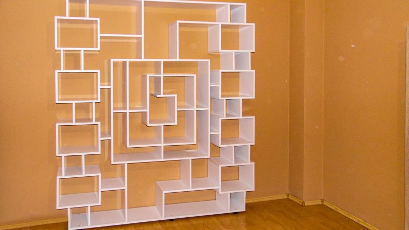 Perspectivă a etajerei albe de perete, într-o lumină ambientală, care accentuează formele geometrice și designul sculptural.
