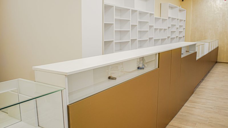 Vedere laterală a liniei de tejghele cu front auriu și blat alb mat, mobilier comercial la comandă