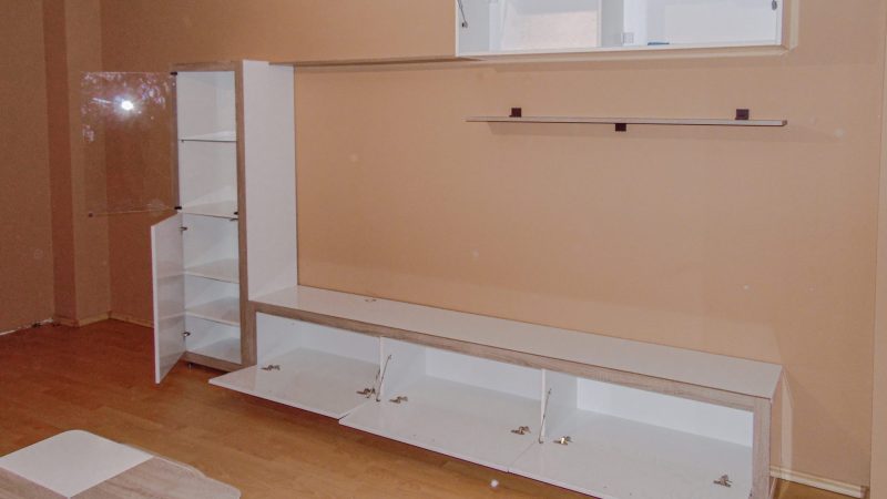 Interiorul unui corp de mobilier pentru living cu uși deschise, etalând spațiile de depozitare inteligent compartimentate.