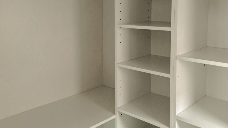 Prim-plan cu o bară de haine metalică, finisaj cromat mat, montată sub o poliță într-un dressing pe comandă din PAL alb.