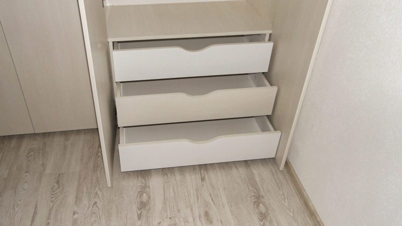 Armonia unui proiect stă adesea în detaliile tehnice. În interiorul acestui dressing am prevăzut trei sertare generoase, ideale pentru a organiza accesoriile mici. Alegerea mânerelor decupate direct în frontul sertarelor are un dublu rol. Pe de o parte, păstrează o linie vizuală curată. Pe de altă parte, este o decizie esențială care permite închiderea perfectă a ușilor, fără ca mânerele acestora să lovească sertarele. Astfel, am putut păstra adâncimea maximă a fiecărui sertar, fără a irosi niciun centimetru prețios din interior.