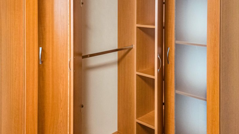 Interiorul corpului central al dressingului pe colț, cu două bare pentru umerașe și o coloană de rafturi.