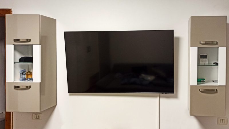 Corpuri suspendate din MDF lucios bej, cu mânere metalice și polițe interioare din sticlă, parte dintr-un mobilier de living modern realizat în Timișoara.