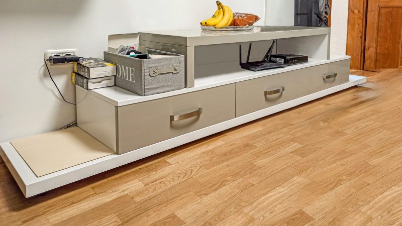 Prim-plan cu cele trei sertare ale corpului inferior de la un mobilier de living modern, cu fronturi din MDF bej lucios și mânere metalice.