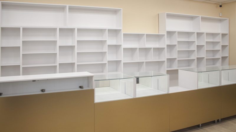 Ansamblu mobilier comercial, combinând tejgheaua aurie cu vitrine și sistemul de rafturi albe din spate