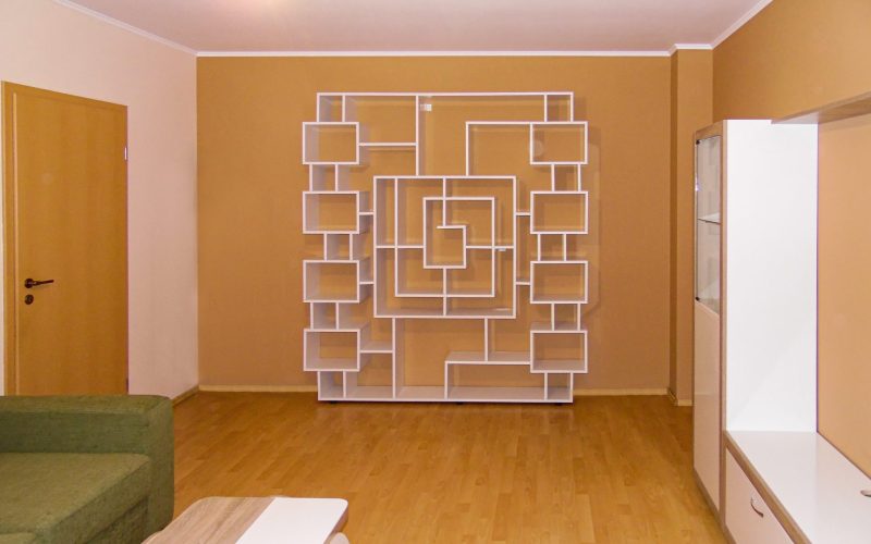 Etajeră albă de perete cu design modern, având o structură creativă cu cadre și nișe asimetrice, folosită ca galerie personală.