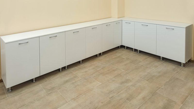 Linie de corpuri joase de depozitare pe colț, din pal alb mat, cu picioare reglabile