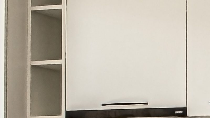 Detaliu cu o etajeră suspendată îngustă, de culoare albă, montată pe perete deasupra blatului, integrată în designul unei bucătării moderne.