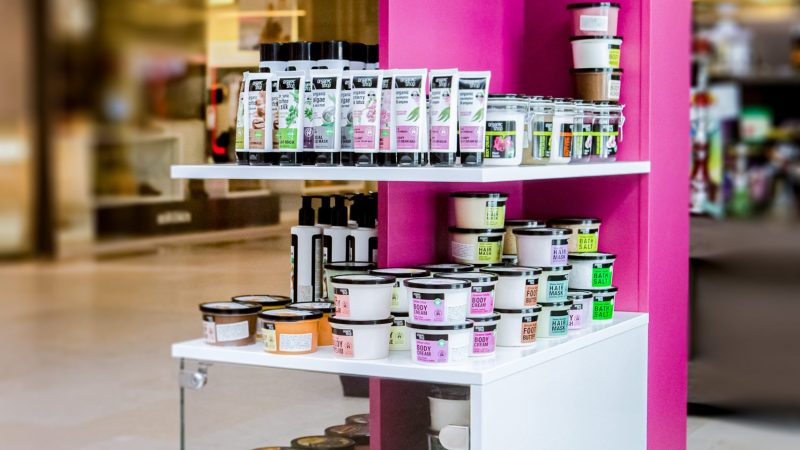 Stand de expunere produse cosmetice din PAL roz dublat cu rafturi deschise.