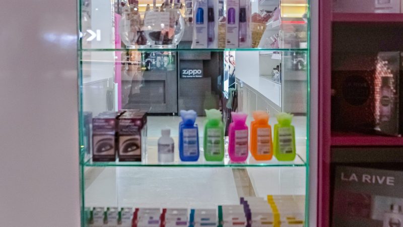 Vitrina cub din sticla securizata cu yala si polite, asezata pe suport din PAL alb.