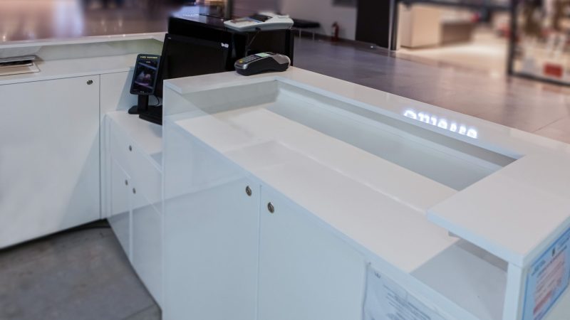 Vedere interioara mobilier receptie cu spatii de depozitare si blat de lucru alb.